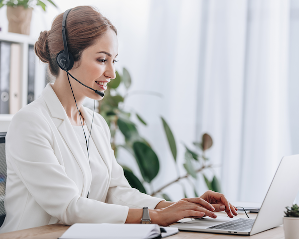 Women wearing headset typing on laptop.